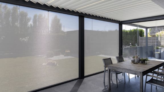 Outdoor roller shades installed on a patio enclosure