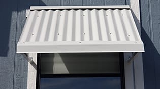 Residential corrugated metal grey window awnings.