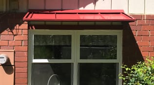 Residential aluminum window awnings painted red.